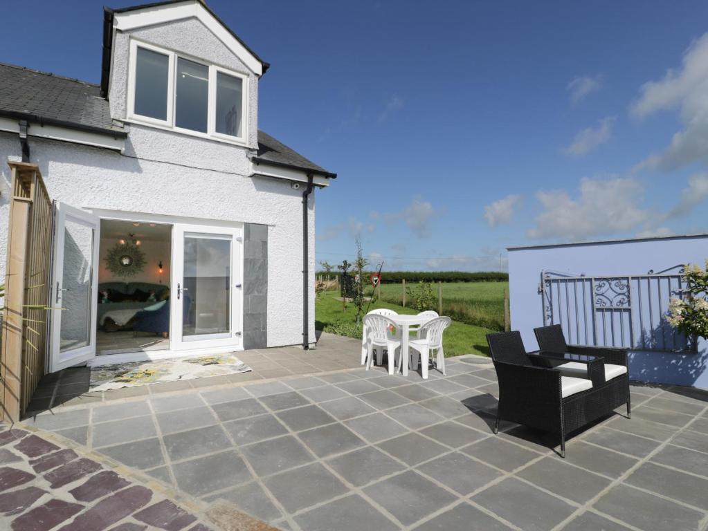 a patio with a table and chairs and a house at Drws y Gorlan in Llanerchymedd