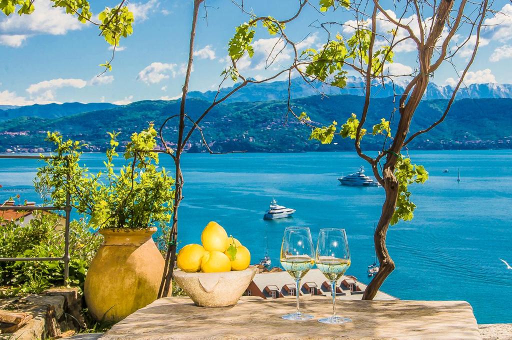 een tafel met glazen wijn en uitzicht op het water bij VILLA CASTELLo PORTOVENERE in Portovenere