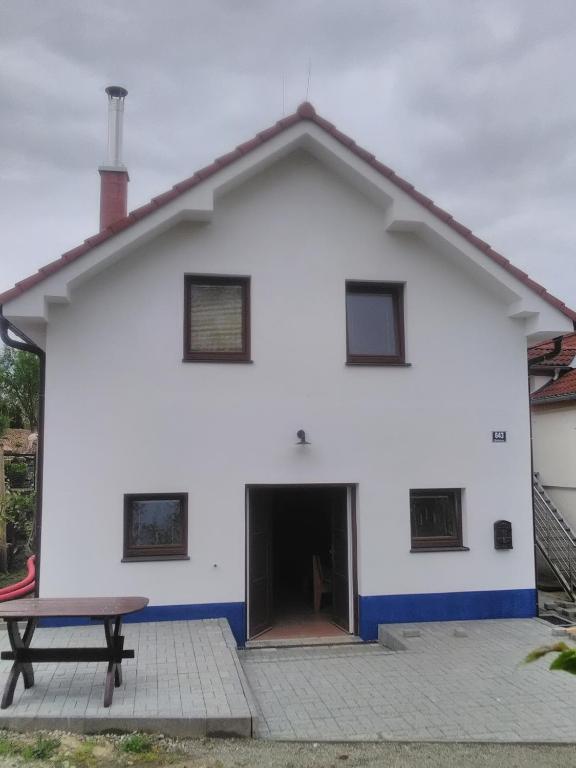 una casa blanca con una mesa de picnic delante de ella en Sklípek u cyklostezky en Březí