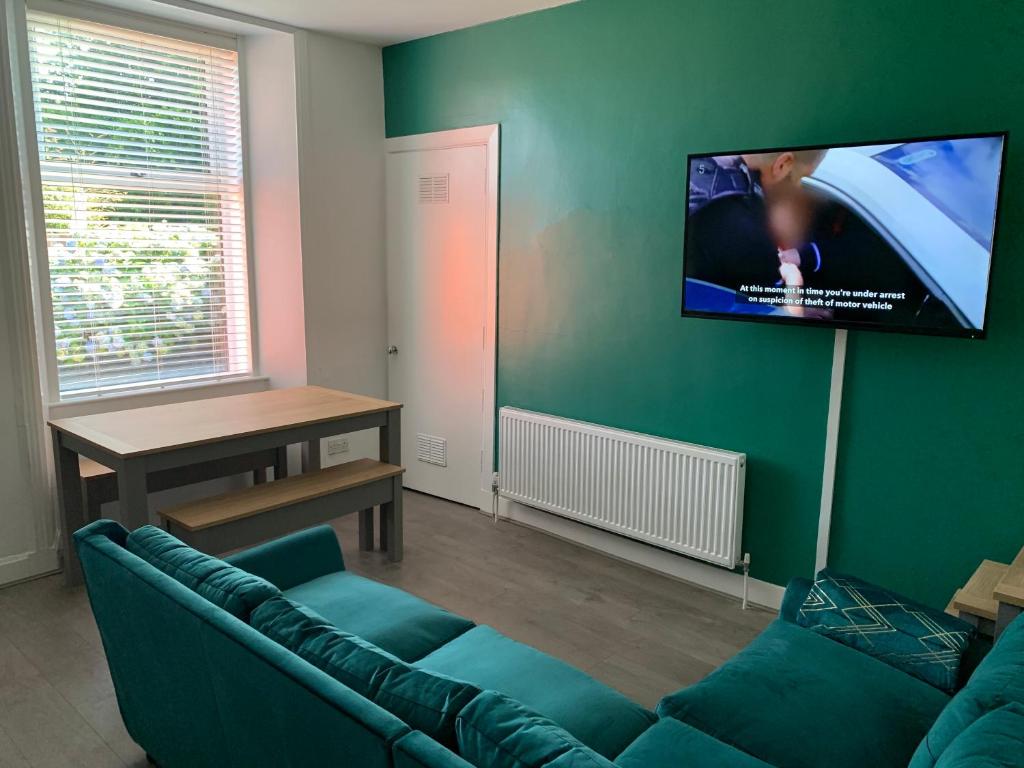sala de estar con sofá y TV de pantalla plana en Woodvale Flat, Renton, Loch Lomond, en Renton