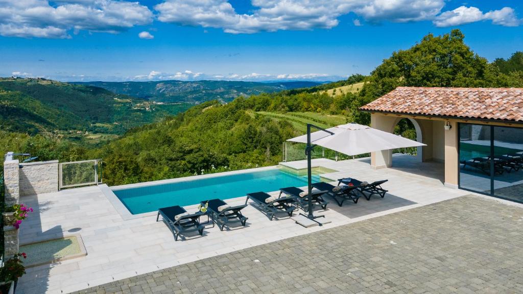 basen z krzesłami i parasolem oraz dom w obiekcie Villa Grazia - with heated salt water Pool w mieście Pazin