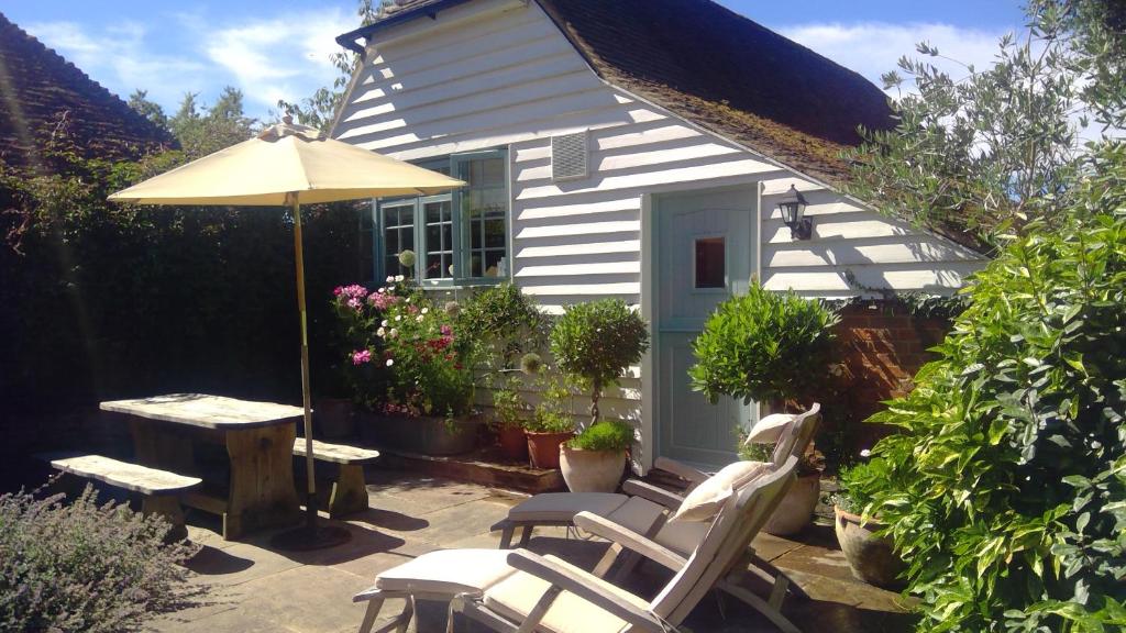 a patio with chairs and a table and an umbrella at Freshwater Barn in Benenden