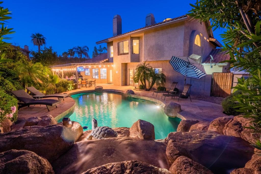 a swimming pool with a waterfall in front of a house at Premier Hosts present Scottsdale Luxury Oasis with Lagoon Pool in Phoenix