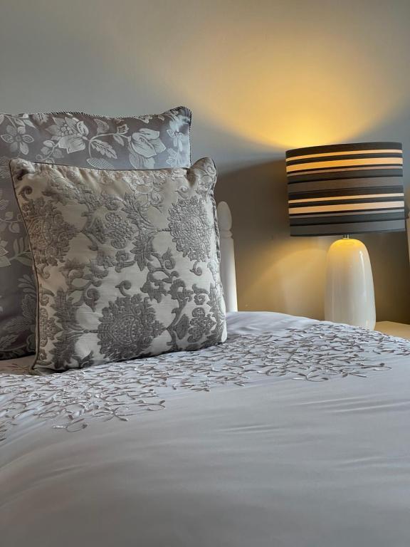 a bed with a white comforter and pillows at Greenfields Country House in Latton