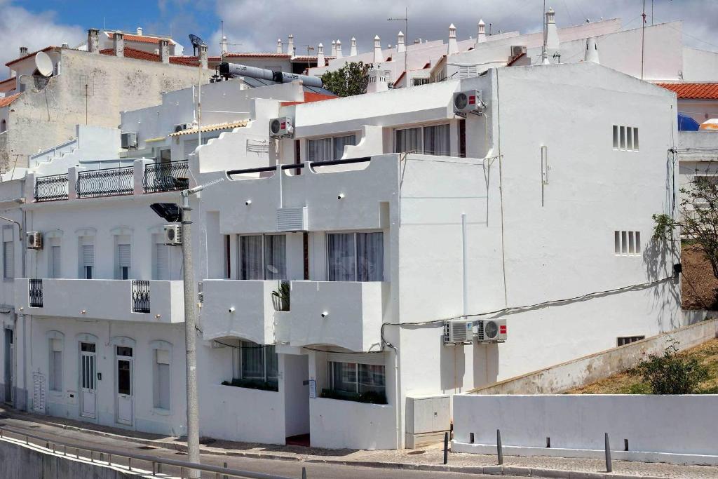 biały budynek na zboczu wzgórza w obiekcie Apartamentos Pescadores w Albufeirze