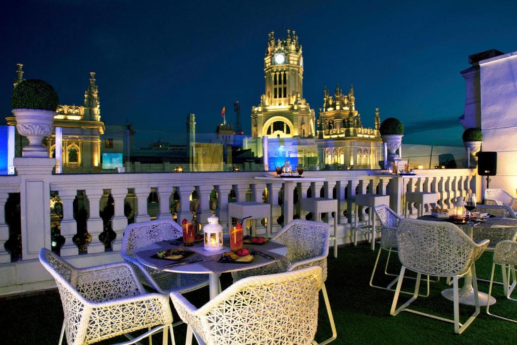 a table and chairs on a balcony with a clock tower at Boutike Cibeles in Madrid