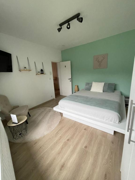 a bedroom with a white bed and a wooden floor at Le Revella in Profondeville