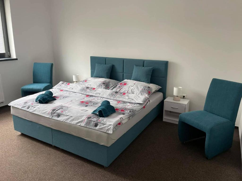 1 dormitorio con 1 cama y 2 sillas azules en RetroDym penzion, en Vranov nad Topľou