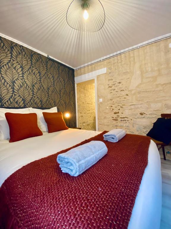 a bedroom with a bed with two towels on it at Chambres d'hôtes Le Maroni in Courseulles-sur-Mer
