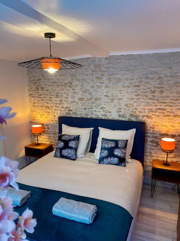 a bedroom with a bed with pillows and a brick wall at Chambres d'hôtes Le Maroni in Courseulles-sur-Mer