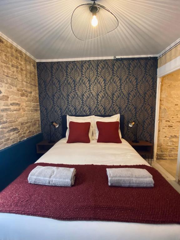 a bedroom with a large bed with two red pillows at Chambres d'hôtes Le Maroni in Courseulles-sur-Mer