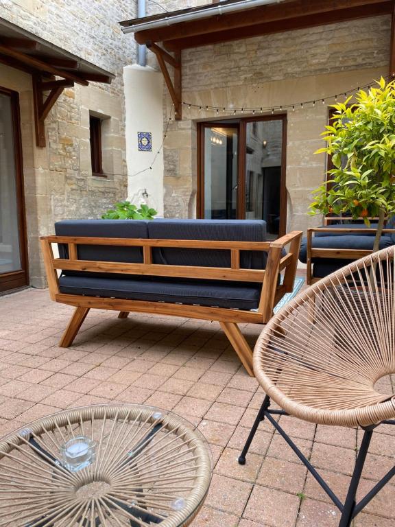 a bench and two chairs on a patio at Chambres d'hôtes Le Maroni in Courseulles-sur-Mer