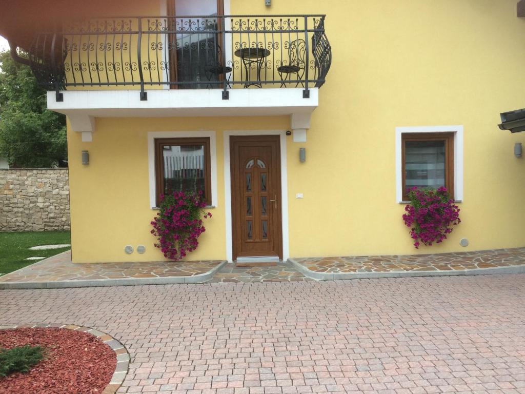 żółty dom z balkonem i drzwiami w obiekcie Casa Vacanza CADORNA RESIDENCE w mieście Tarvisio