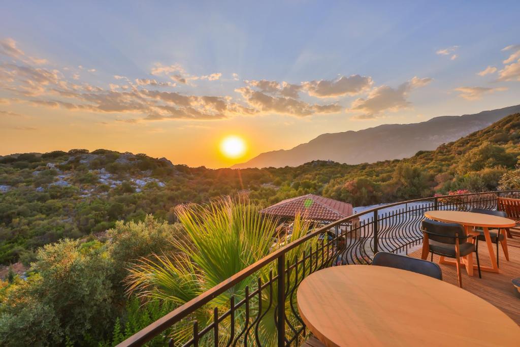 a balcony with tables and chairs and the sunset at Hill House Adult Only in Kaş