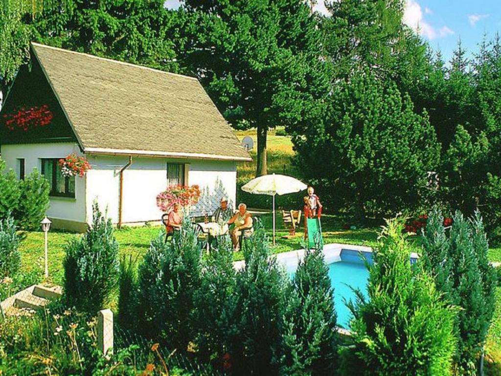 Un groupe de personnes assises à une table à côté d'une maison dans l'établissement Holiday Home in Altenfeld with Private Pool, à Altenfeld