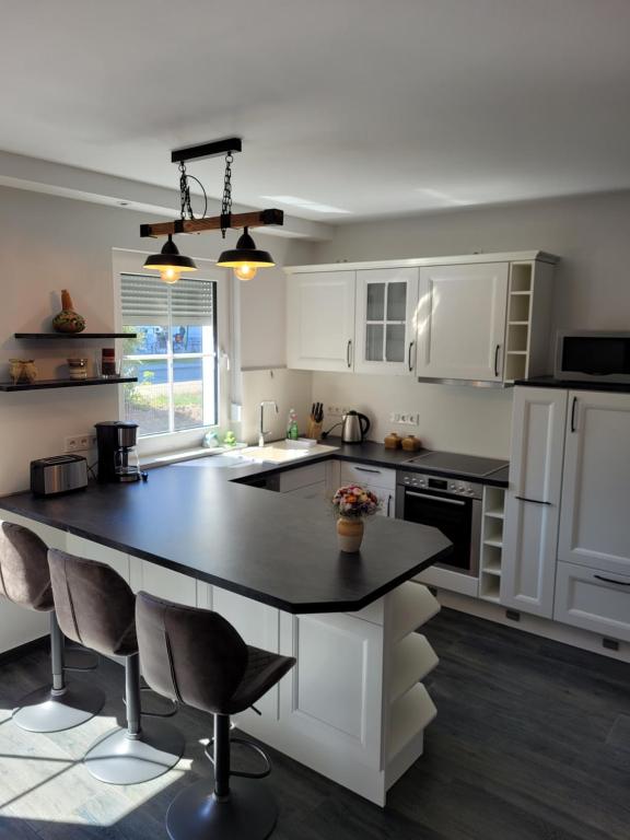 a kitchen with white cabinets and a black counter top at Spreewaldblick in Lübben