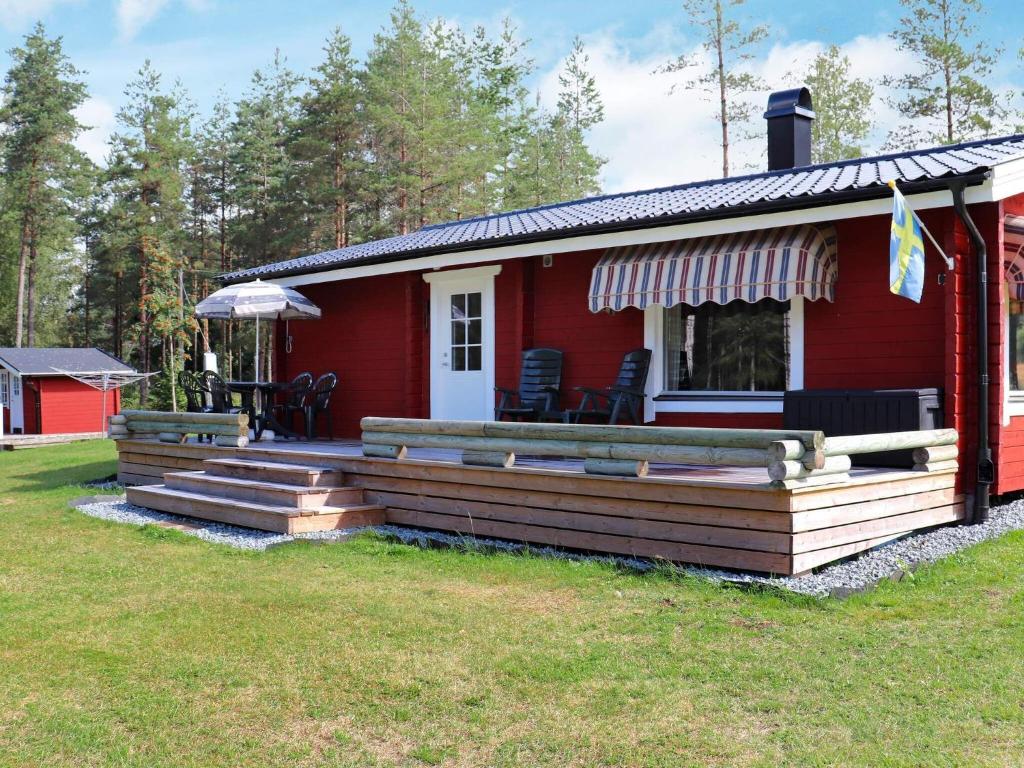ein rotes Haus mit einer Terrasse davor in der Unterkunft Holiday home DALS-LÅNGED in Dals Långed