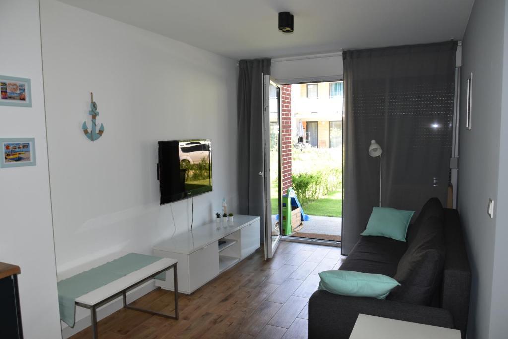 a living room with a couch and a tv at Apartament Rodzinny Jantar Park in Jantar