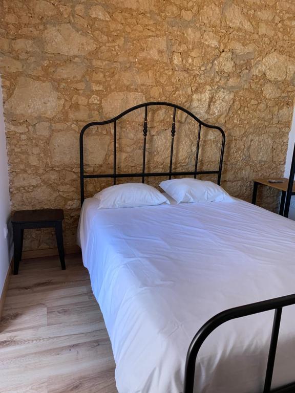 a bed in a bedroom with a stone wall at QuimPecável in Figueira da Foz
