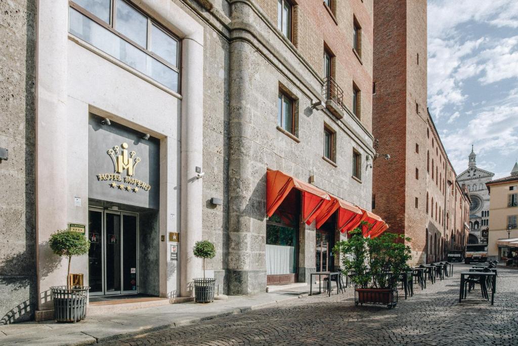 a street with tables and chairs in front of a building at Hotel Impero in Cremona