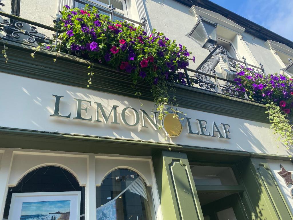a sign for a store with flowers on the facade at The Lemon Leaf Café Bar and Townhouse in Kinsale