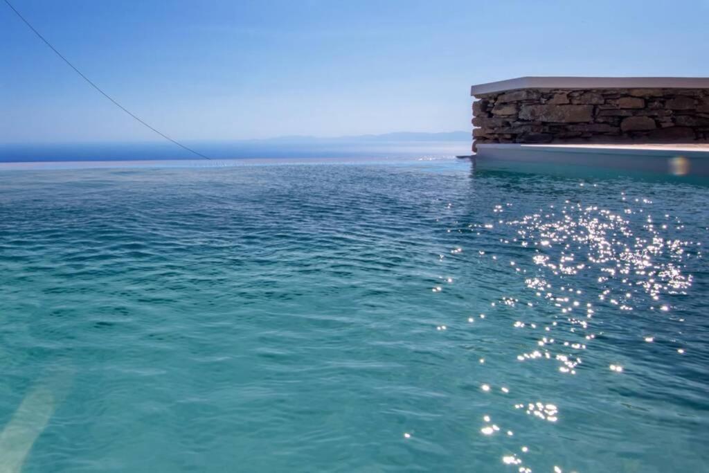 un corpo d'acqua con un muro di pietra e l'oceano di Villa Leonora Tinos ad Arnádhos