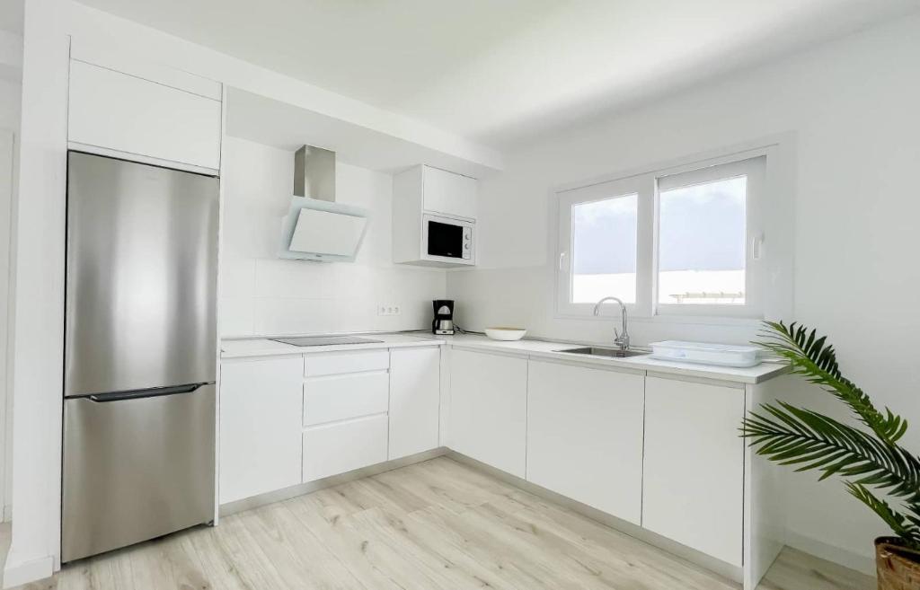 a kitchen with white cabinets and a stainless steel refrigerator at Island Home Fuerteventura in Corralejo