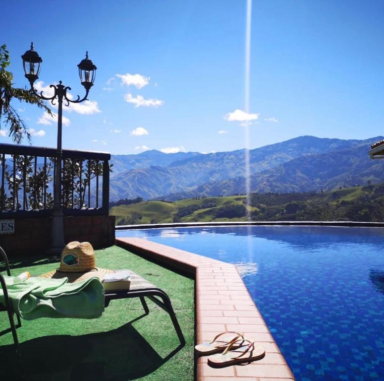 una persona sentada en una silla junto a una piscina en Castillo de Cascadas Finca Hotel, en Salamina