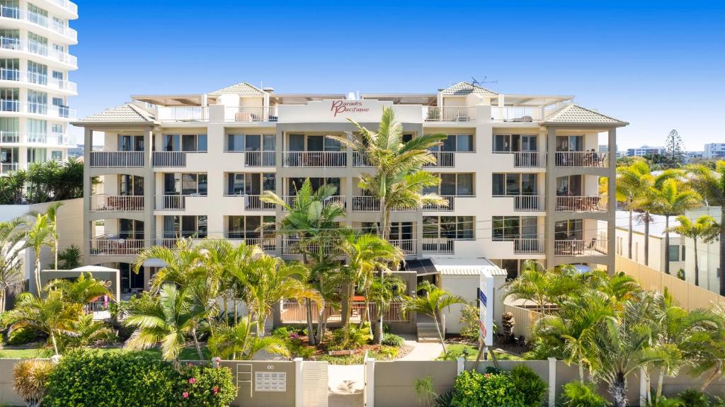 馬盧奇多的住宿－太平洋天堂公寓酒店，一座白色的大建筑,前面有棕榈树