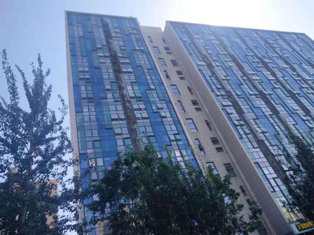 un edificio alto con ventanas de cristal azul. en Chaoyang Joy City Hardcover Apartment, en Beijing