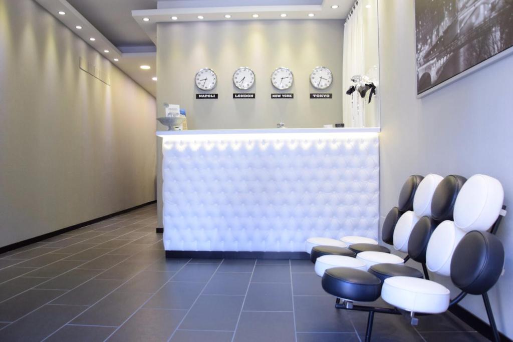 een wachtkamer met klokken aan de muur en stoelen bij Fly Boutique Hotel in Napels