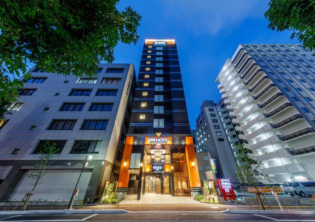 dwa wysokie budynki w mieście w nocy w obiekcie APA Hotel Hakata Ekimae 2Chome w mieście Fukuoka