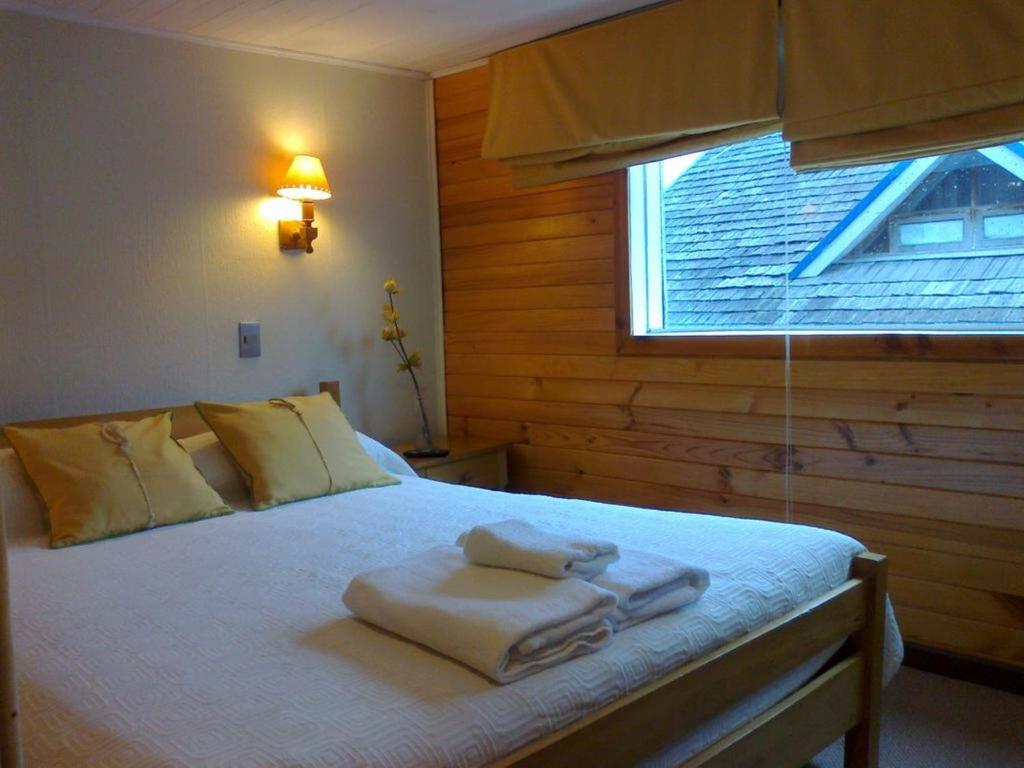 1 dormitorio con 1 cama con toallas en Ancud Petit Hostal, en Ancud