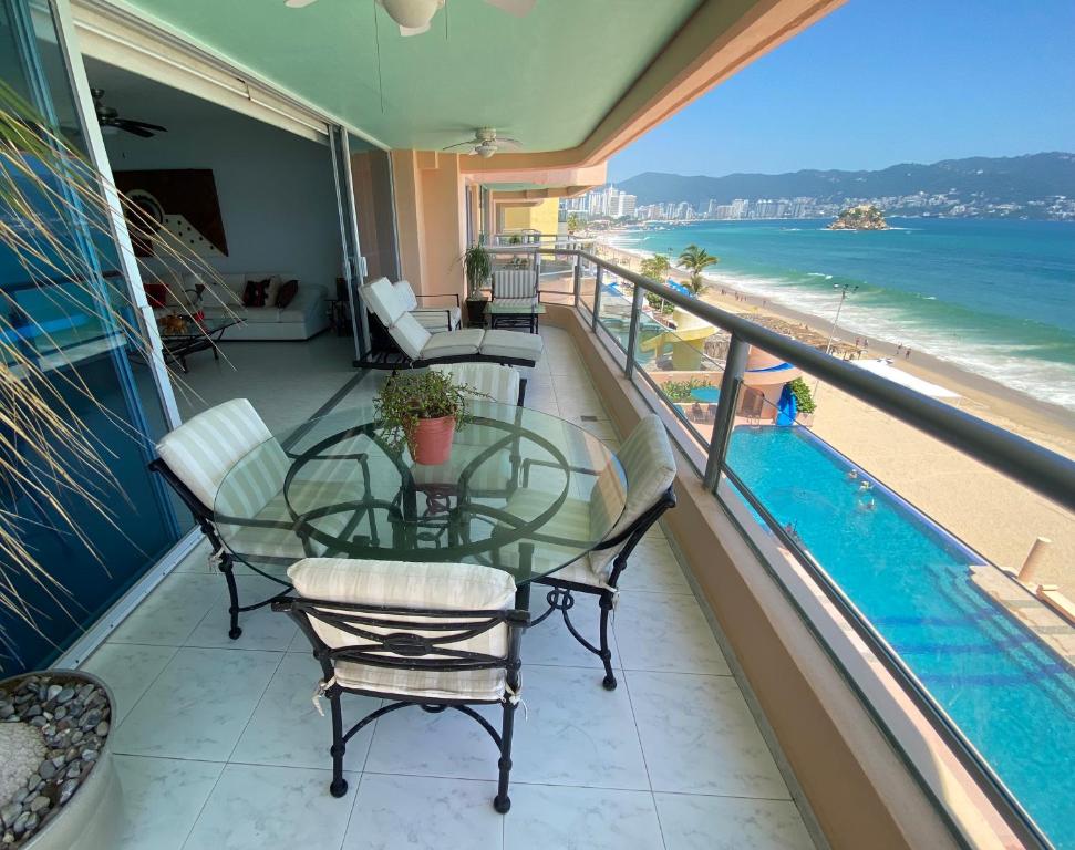 uma varanda com mesa e cadeiras e vista para a praia em Comfortable Beachfront apartment in Acapulco em Acapulco