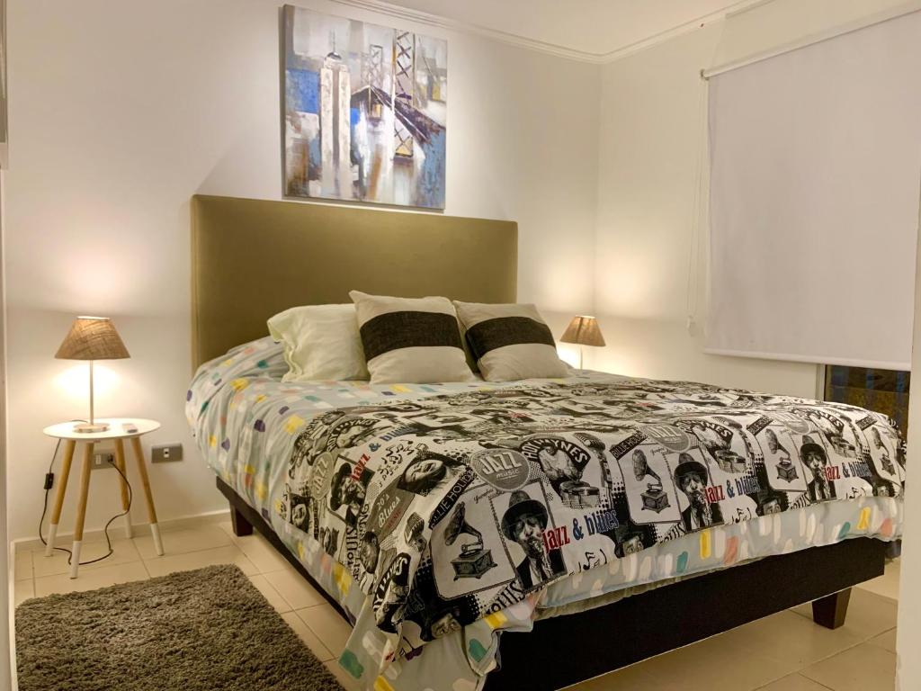 1 dormitorio con 1 cama con edredón blanco y negro en Apart Mejillones - Dpto 22 en Mejillones
