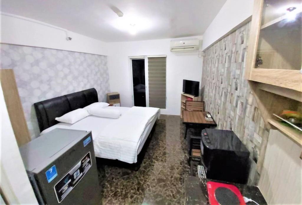 a hotel room with a bed and a desk at Apartemen Mutiara Bekasi by Veeroom in Bekasi