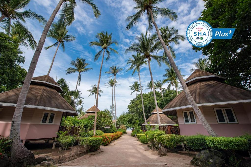 a couple of houses and palm trees on a street at Koh Tao Coral Grand Resort in Koh Tao