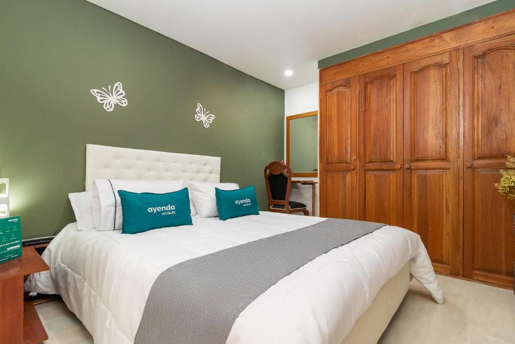 ein Schlafzimmer mit einem großen Bett mit blauen und weißen Kissen in der Unterkunft Ayenda Dorado Boutique in Bogotá