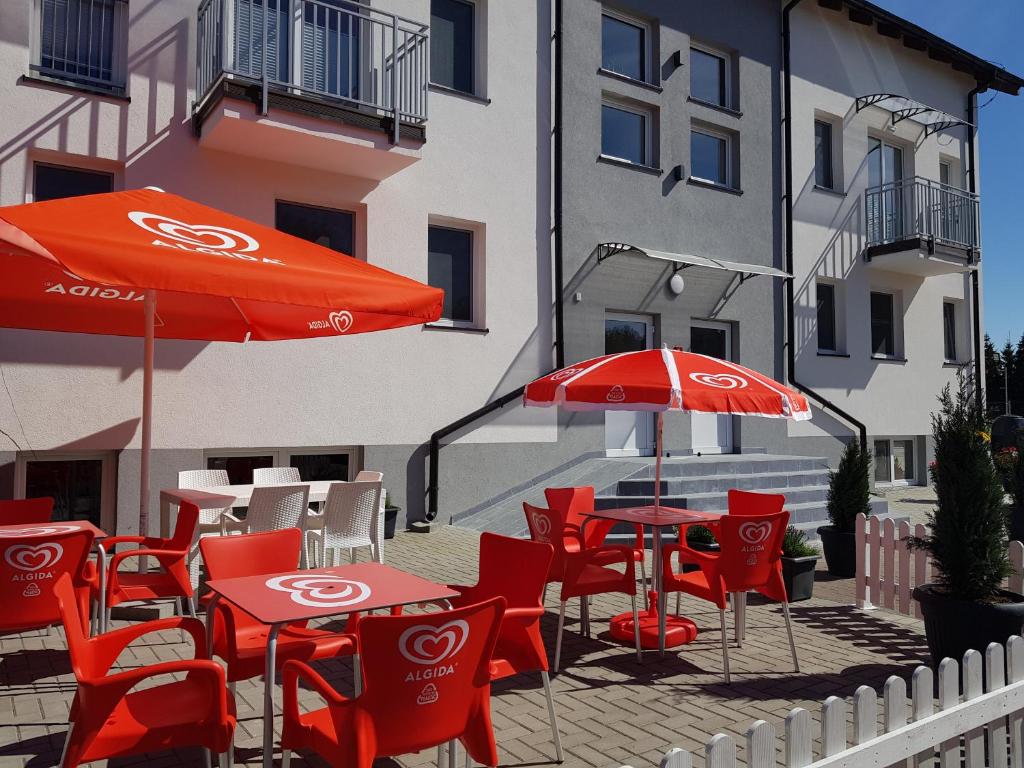 a patio with red tables and chairs and umbrellas at Siedlisko na Zaciszu Gościniec in Kąty Rybackie