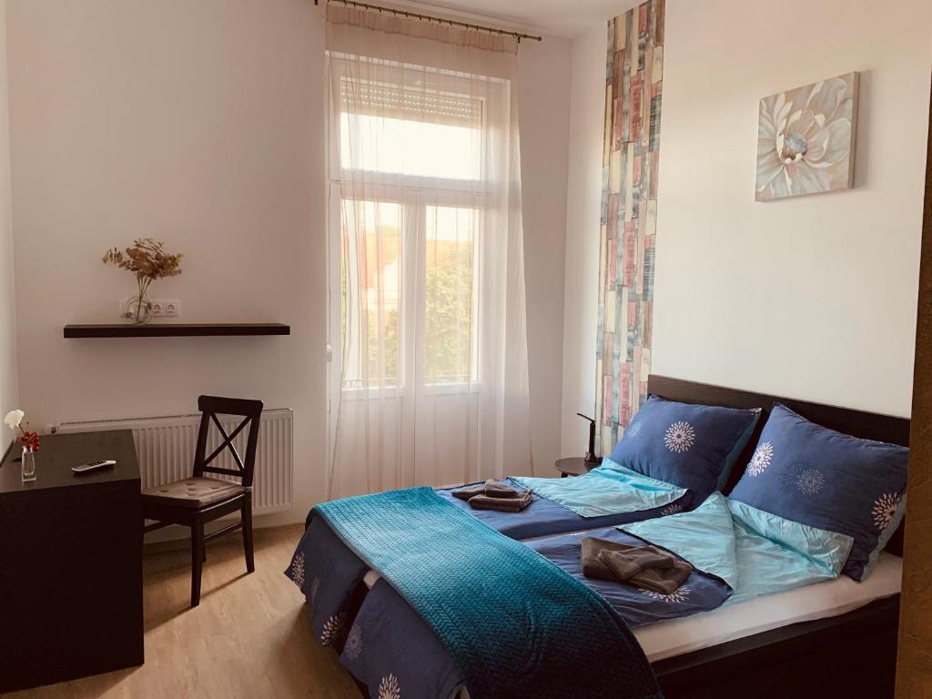 Schlafzimmer mit einem Bett mit blauer Bettwäsche und einem Fenster in der Unterkunft West Residence in Budapest
