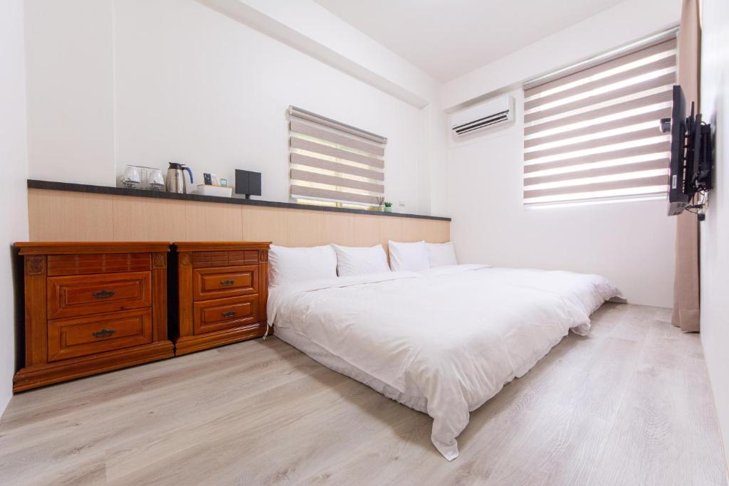 a bedroom with a white bed and a wooden dresser at 向晴民宿 花蓮市包棟民宿 in Hualien City