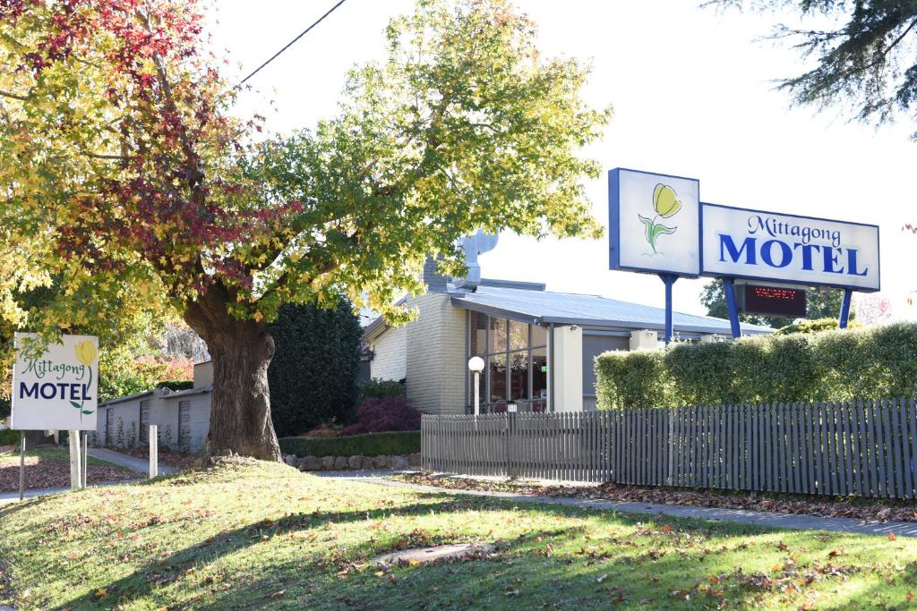 a motel sign in front of a building with a tree at Mittagong Motel in Mittagong