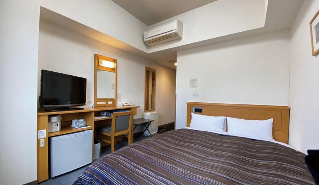 Habitación de hotel con cama y escritorio en Hotel Route-Inn Tsubamesanjo Ekimae, en Sanjo