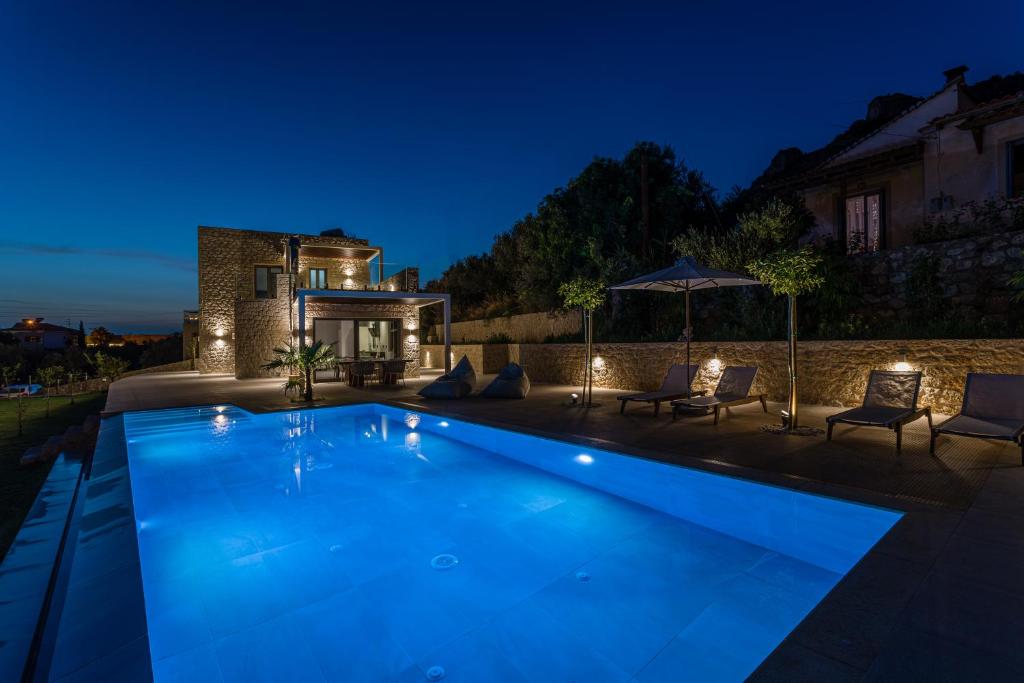 una piscina frente a una casa por la noche en Manitennisvillas, en Stoupa