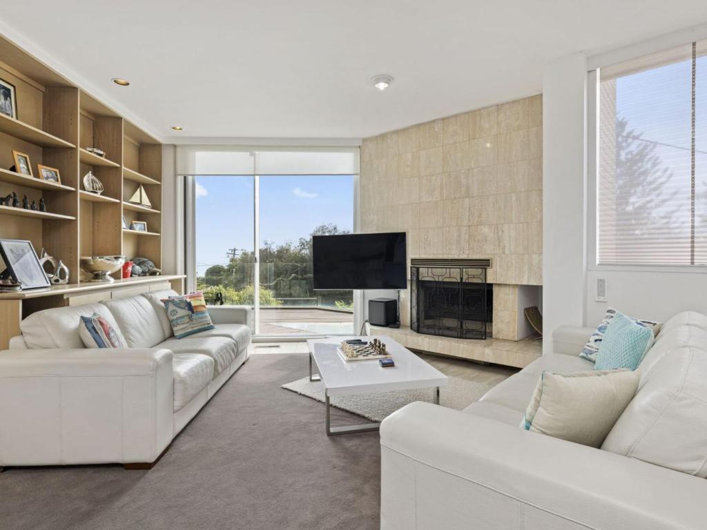 a living room with white furniture and a fireplace at Blue Horizon Mt Eliza in Mount Eliza