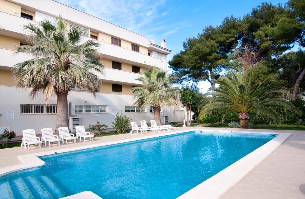a swimming pool in front of a building with palm trees at Drac Blanc 1-4 in Cala Ratjada