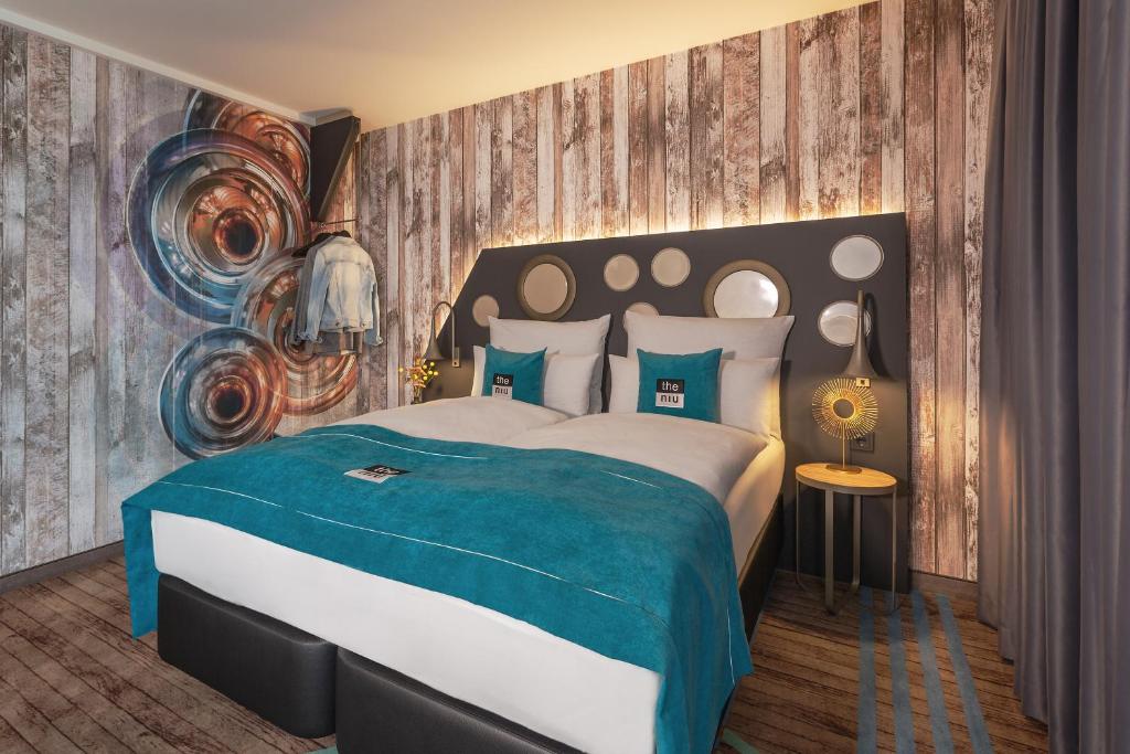 ein Schlafzimmer mit einem großen Bett mit einer blauen Decke in der Unterkunft the niu Brass in München