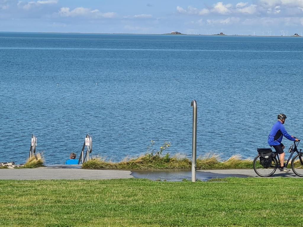 a person riding a bike next to the water at Lütt Moor in Nordstrand