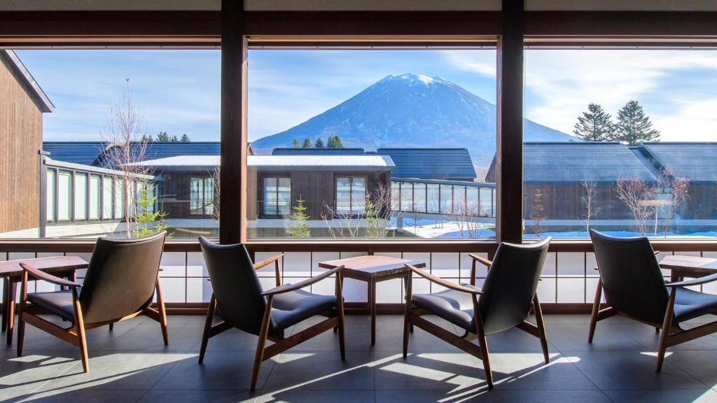 a room with a table and chairs and a mountain view at NISEKO Inn of Youtei Raku Suisan in Kutchan