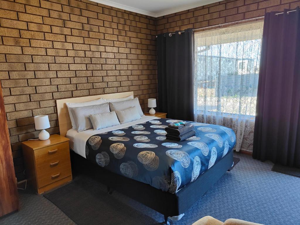 ein Schlafzimmer mit einem Bett und einer Ziegelwand in der Unterkunft Airport Whyalla Motel in Whyalla